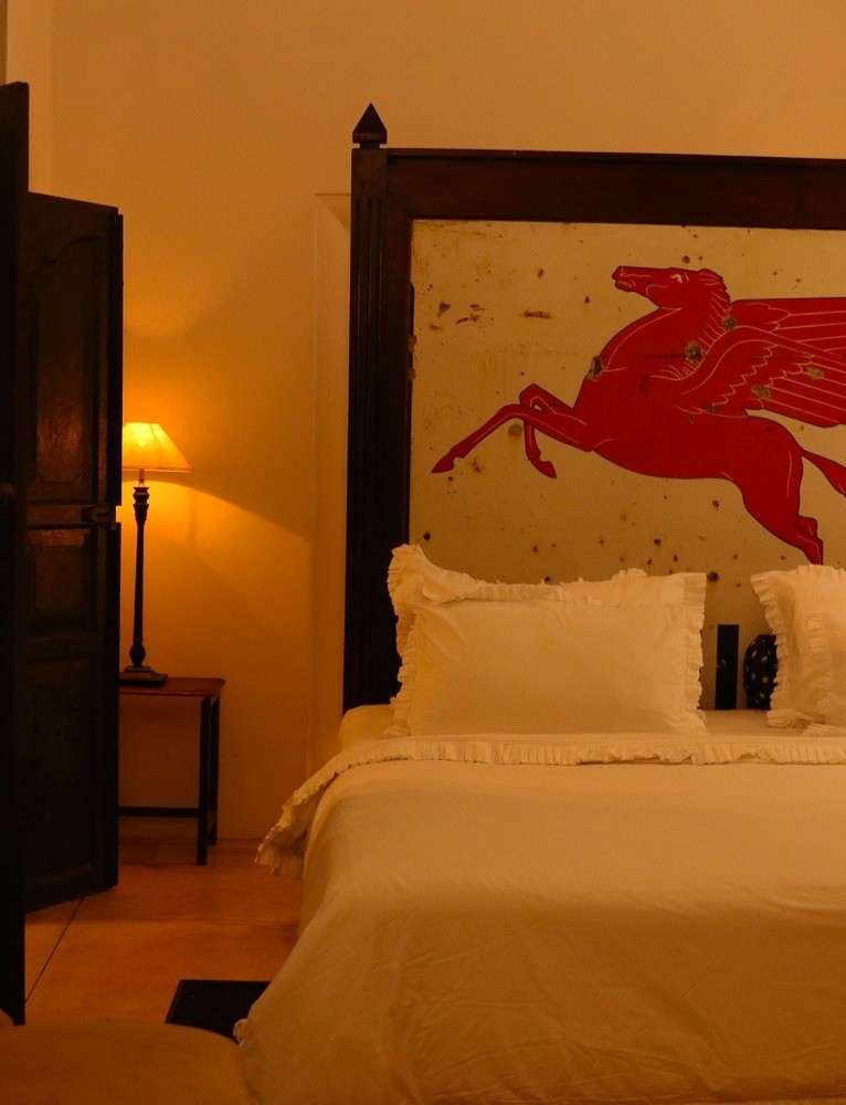 A red winged horse painted across a weathered white panel that forms the bedhead.